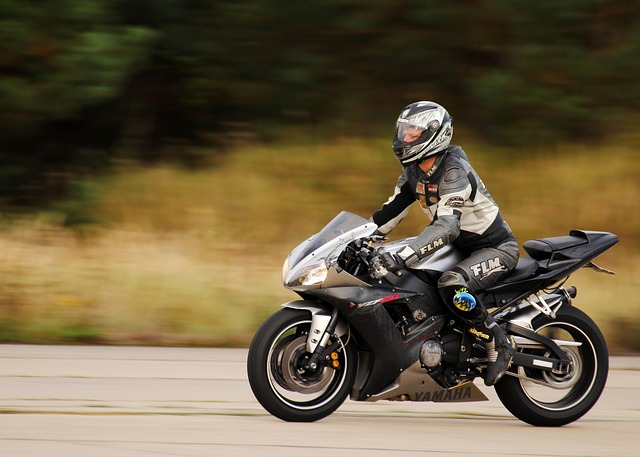 Muž v motorkárskej kombinéze s integrálnou prilbou ide na motorke.jpg
